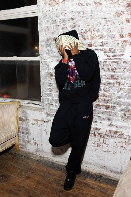 RodSlime leaning on a brick wall with cash held over his face.